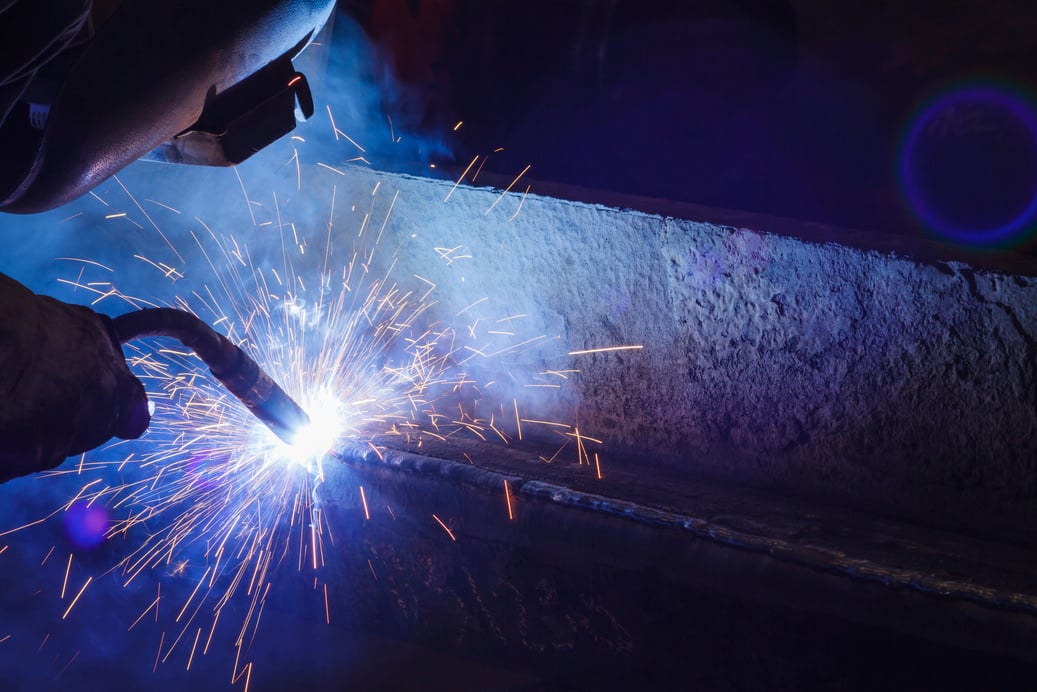 Worker welding steel by MIG-MAG weld (Argon welding).